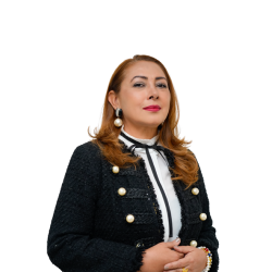DSC2583 Gerente Risaralda, una mujer con cabello castaño rojizo y pendientes de perlas, vestida con una chaqueta negra de tweed adornada con perlas, mira por encima del hombro con las manos cruzadas en el abdomen.